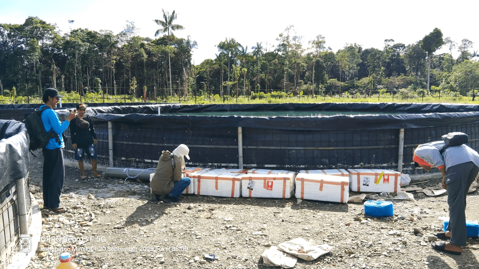 People handling materials beside Area 02 tanks